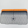 A stack of silicone kitchen sink mats in orange, black, and gray with a faucet splash guard.