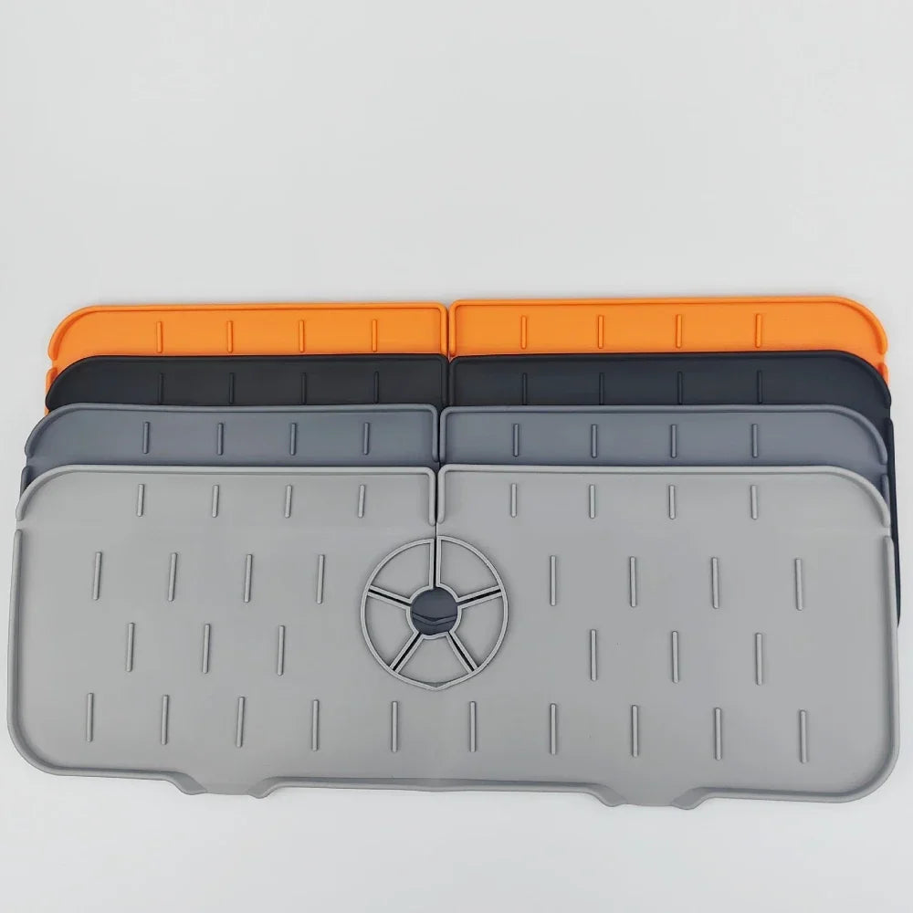 A stack of silicone kitchen sink mats in orange, black, and gray with a faucet splash guard.