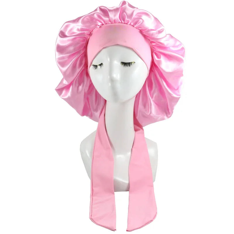 Pink satin sleep cap for hair protection displayed on a mannequin head