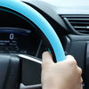 A hand grips a light blue silicone steering wheel cover on a black car steering wheel.