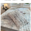 A fluffy, light gray faux fur fitted sheet and matching pillowcases are displayed on a bed with natural light.