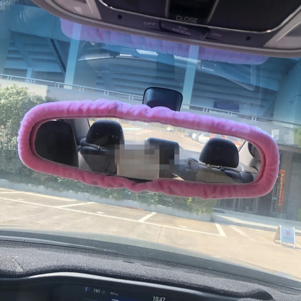 Rearview mirror covers made of pink plush material installed on a car interior.