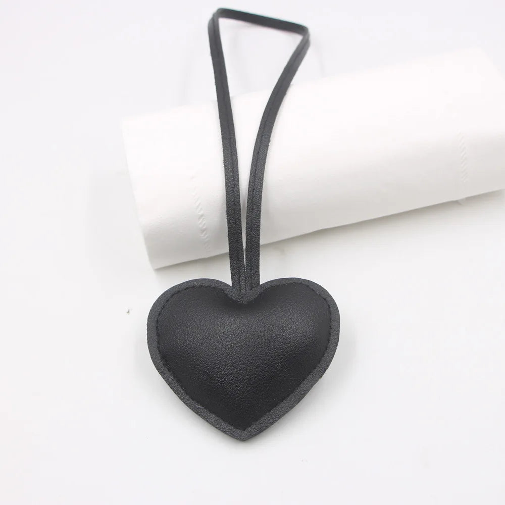 Black heart-shaped PU leather keychain with a cotton peach charm