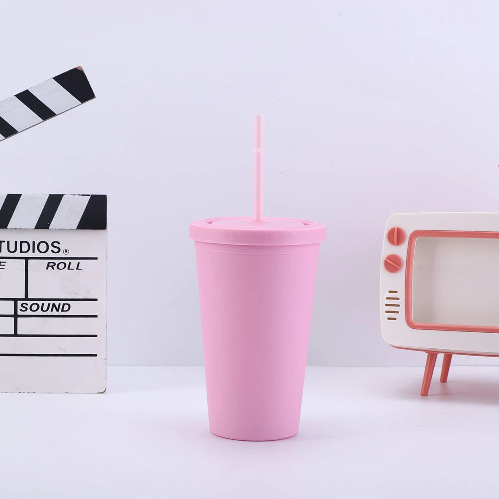 Un tumbler en acrylique mat rose avec une paille, à côté d'un cassette et d'un four à micro-ondes.