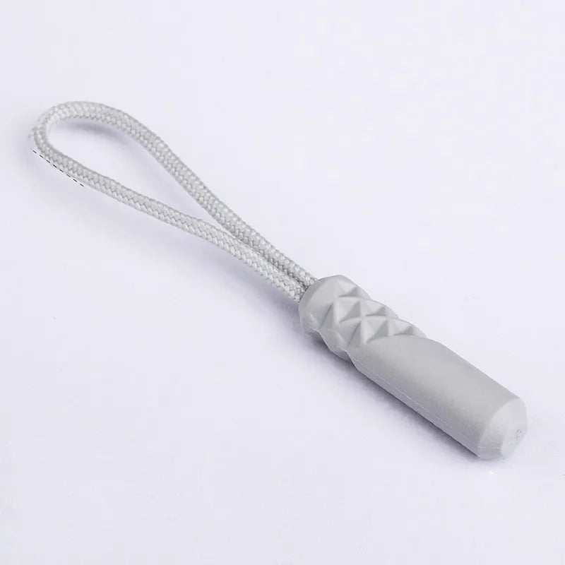 A replacement zipper pull with a silver-colored plastic end and a white nylon cord.