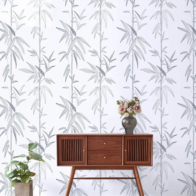 A wooden dresser is displayed against a white wall covered in a gray and green leaf peel-and-stick wallpaper.