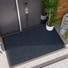 A dark blue hexagonal non-slip doormat placed on a gray tiled floor outside a modern door.