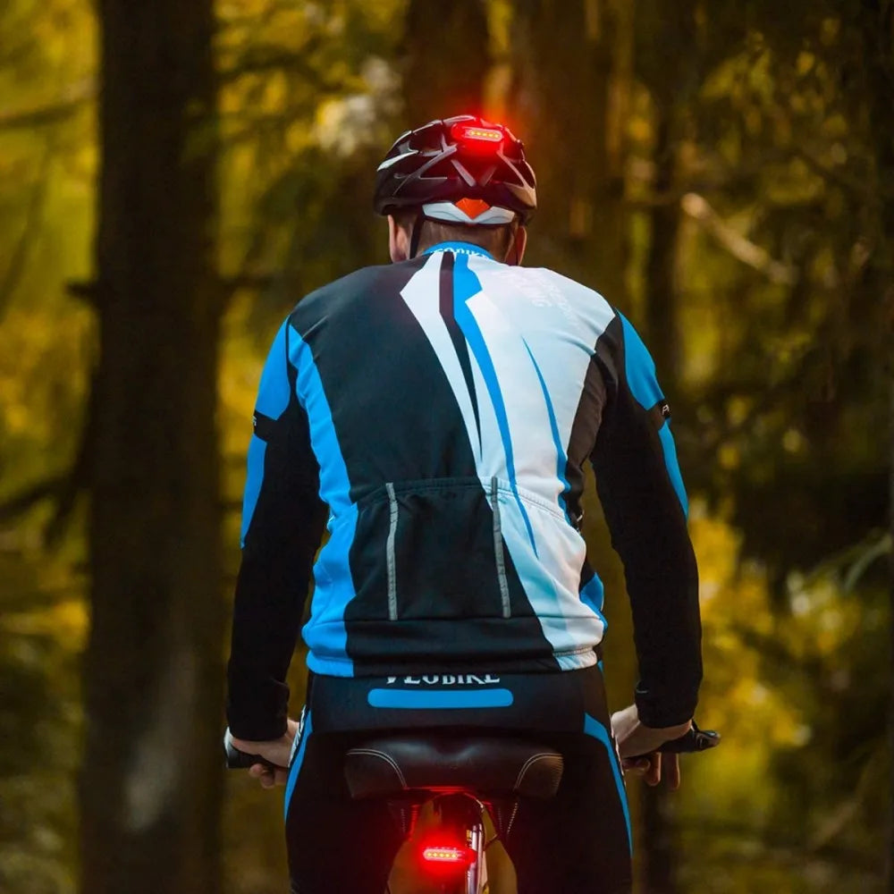A person wearing a cycling jersey is shown from the back, with an illuminated bicycle tail light visible below.