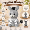 A gray crochet donkey plush toy with black hair, presented as a positive reminder of strength and courage.