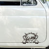 A black vinyl sticker of a shaggy cow face is placed on the white body panel of a car.