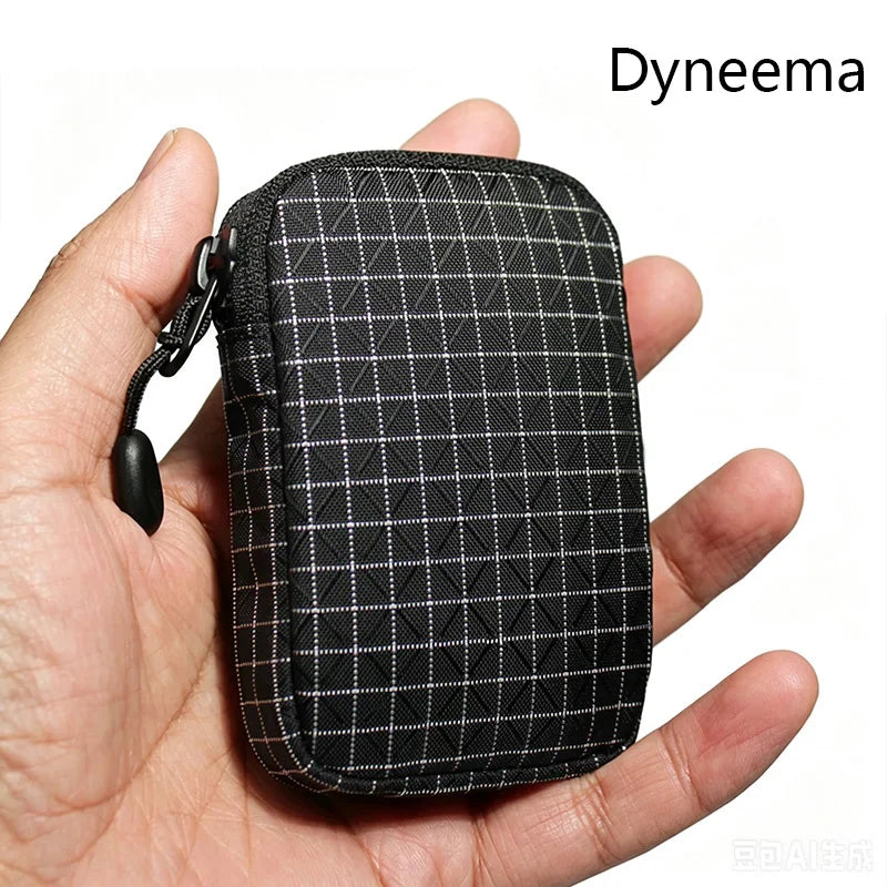 A black Dyneema utility pouch with a checkered pattern is held in a hand.