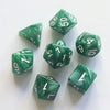 A set of seven green pearl pattern polyhedral dice arranged on a white surface.