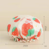 A reusable waterproof shower cap for hair care featuring a strawberry pattern in pink, green, and white.