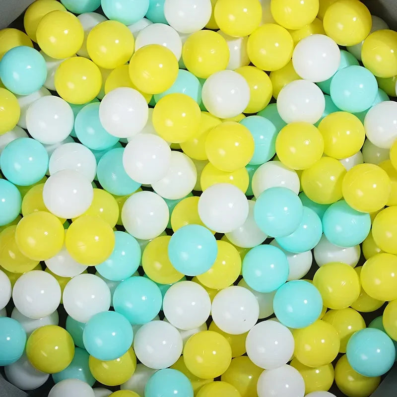 A large pile of colorful plastic ball pit balls in yellow, white, and light blue shades.