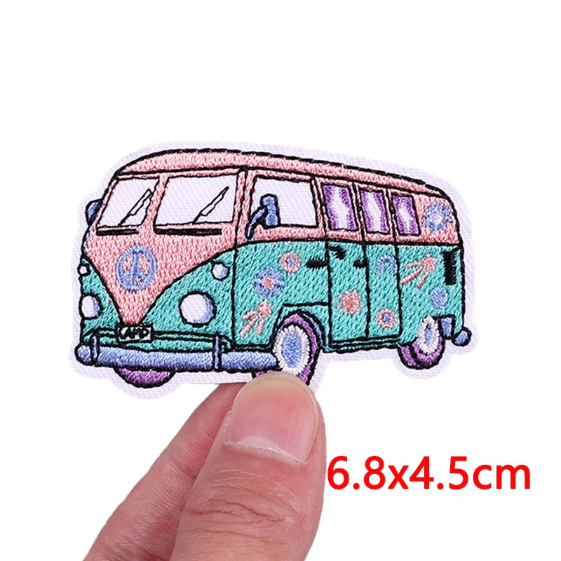 A pink and teal cartoon bus embroidery patch with purple windows and floral details.