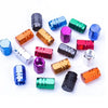 A set of four aluminum alloy wheel tire valve caps in various colors including blue, green, purple, and copper.