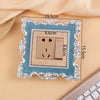 A rectangular switch cover frame with a teal border and silver decorative elements, shown against a light background.