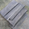 Two stacked black buffalo horn knife handle scales showing wood grain texture on a gray stone surface.