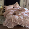 A pink ruffled duvet cover set with matching pillowcases and a decorative throw on a bed.
