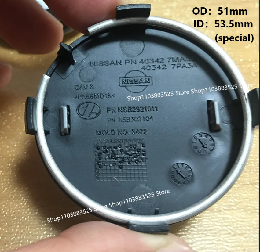 A close-up view of a black wheel center hub cap with Nissan part numbers and dimensions visible.