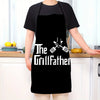 A person wearing a black apron with the text The GrillFather and crossed grilling tools on the front.