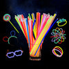 A glass filled with numerous colorful glow sticks and glowing bracelets against a dark, starry background.