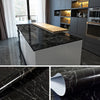 Roll of black marble wallpaper featuring white veining for kitchen and bathroom decor