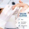 A pair of white disposable salon gloves being worn by a hand applying polish or treatment.