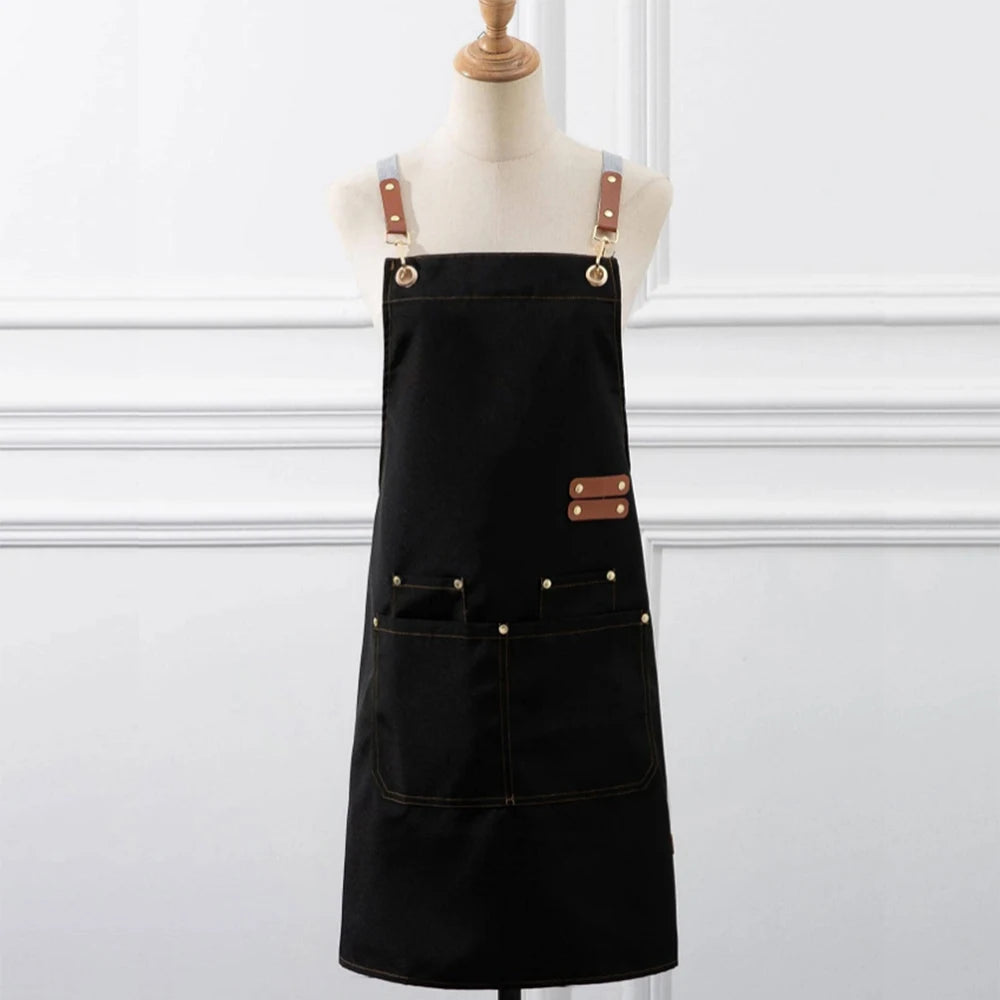 Black canvas kitchen apron with leather straps and large pockets displayed on a mannequin.