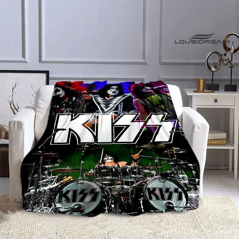 A black and white graphic print of the Kiss band on a flannel throw blanket displayed on a white sofa.