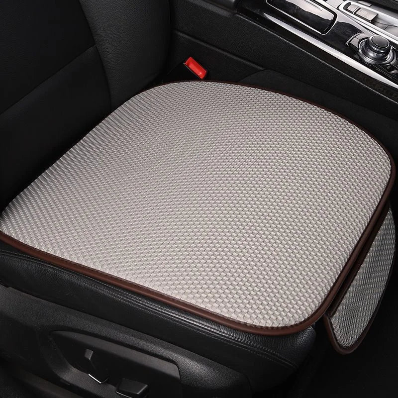 A beige breathable ice silk car seat cushion with a brown trim is shown in a black car interior.