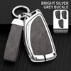A bright silver grey buckle car key case with a leather strap and multiple keys displayed on a black background.