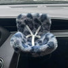 A fluffy blue faux fur vent decoration shaped like a miniature doll seat car is shown inside a car interior.