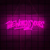A neon sign spelling out THE WORLD IS YOURS in bright pink against a dark purple grid background.