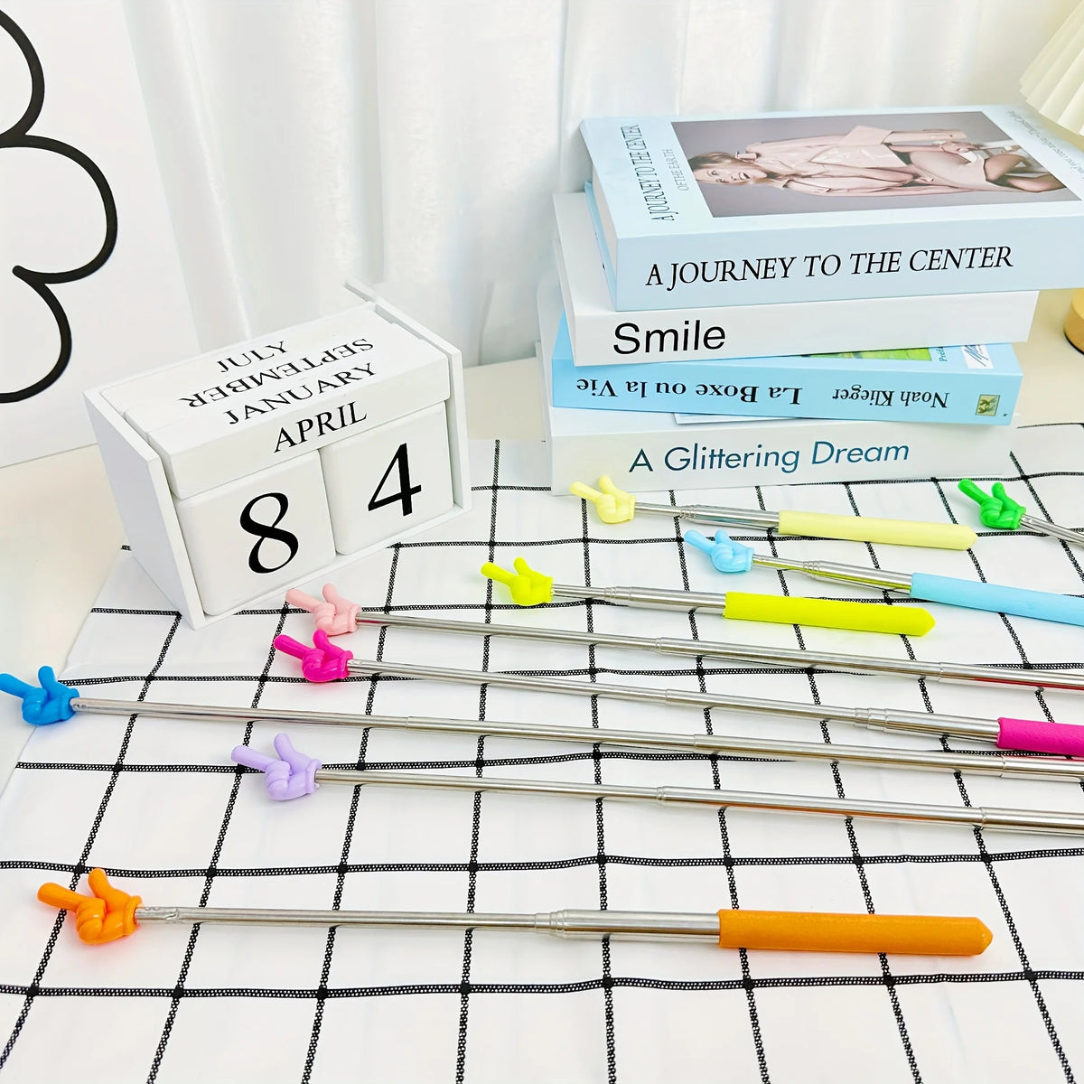 A set of five silver retractable teacher pointers with colored tips are displayed on a white checkered cloth.