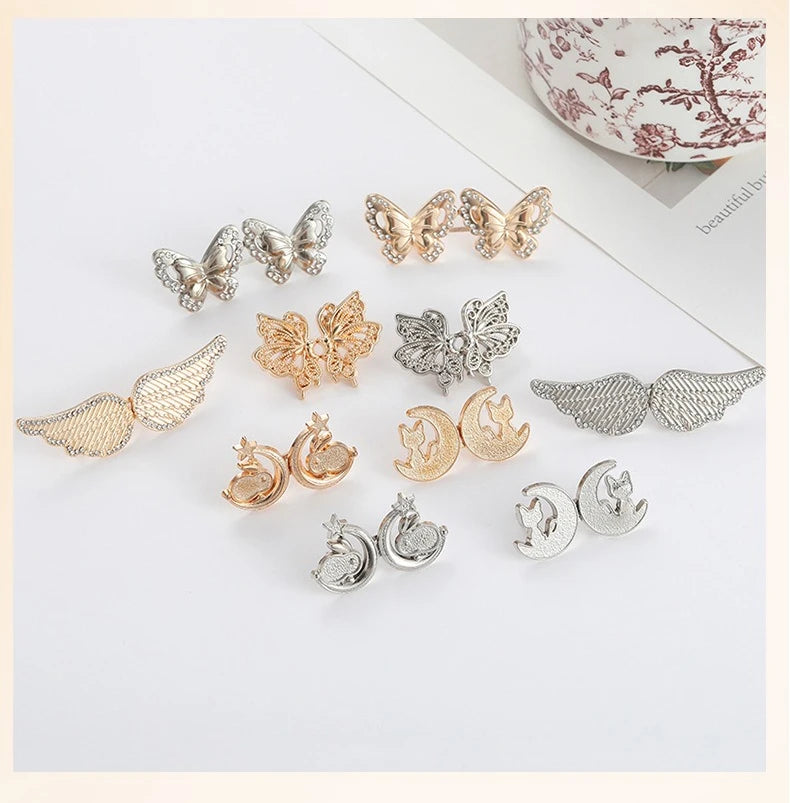 A collection of silver and gold no-sew adjustable waist tightener buttons shaped like butterflies and moons.