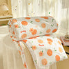 White comforters with an orange peach print and lace trim are displayed on a table near a window.