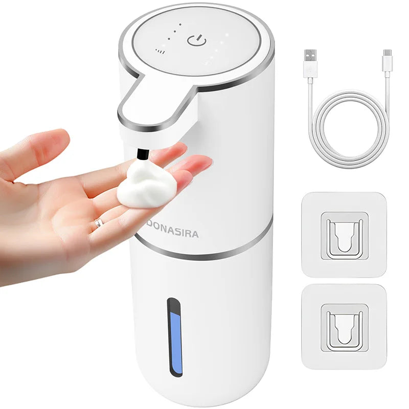 A white touchless automatic soap dispenser is shown being used by a hand, with charging cables and dispensing buttons display