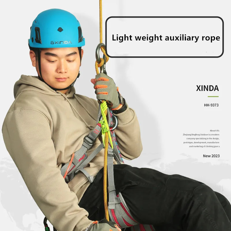 A person wearing a blue helmet is using a light weight auxiliary rope for climbing or descent safety.