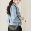 A woman models a dark green compact square crossbody bag with silver hardware and a denim jacket.