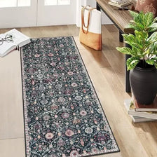 A vintage bohemian trellis runner rug with a dark floral pattern lies on a light wood floor.