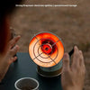 A hand holds a small sun heater with an ignition mechanism, set against a blurred outdoor background.