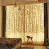 A sheer white curtain decorated with warm fairy lights, illuminating a room.