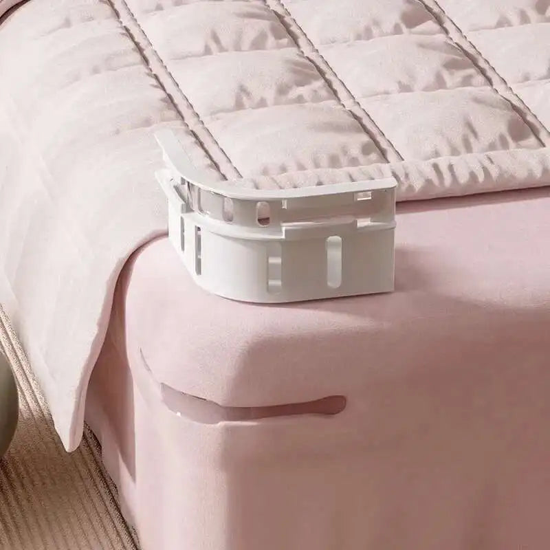 A white no-slip bed sheet holder clip is resting on a pink quilted bed sheet.