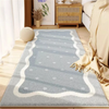 A light blue and white patterned area rug placed on a wooden floor next to a sofa and a wooden cabinet.
