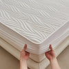 Hands lifting a white floral waterproof fitted mattress protector with a textured surface.
