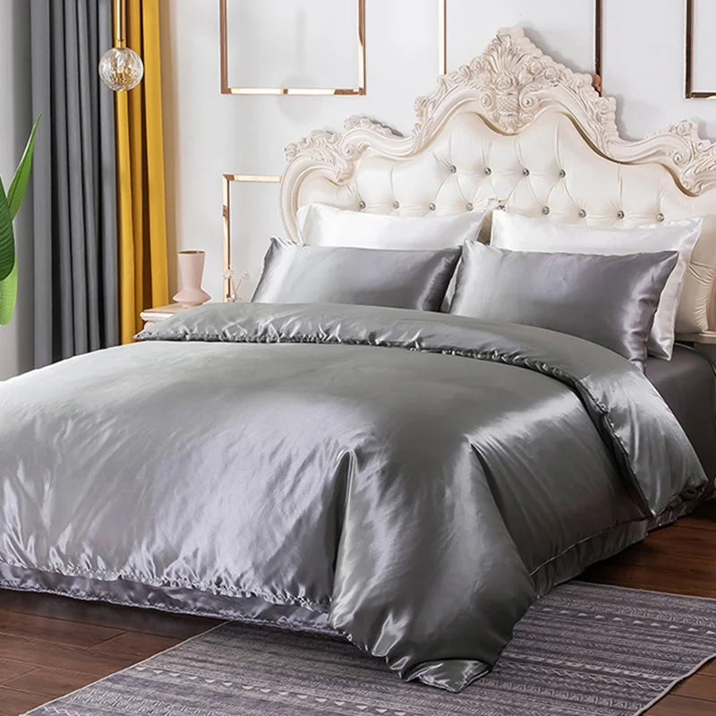 A luxurious silver silky duvet cover set displayed on a bed with a white upholstered headboard and modern decor.