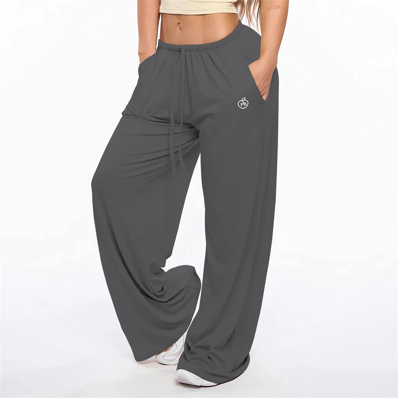 A woman wearing dark gray flare leggings with a drawstring waist and a small logo on the thigh.
