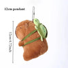 A brown capybara plush toy with a green duck swim ring pendant hanging from a chain.