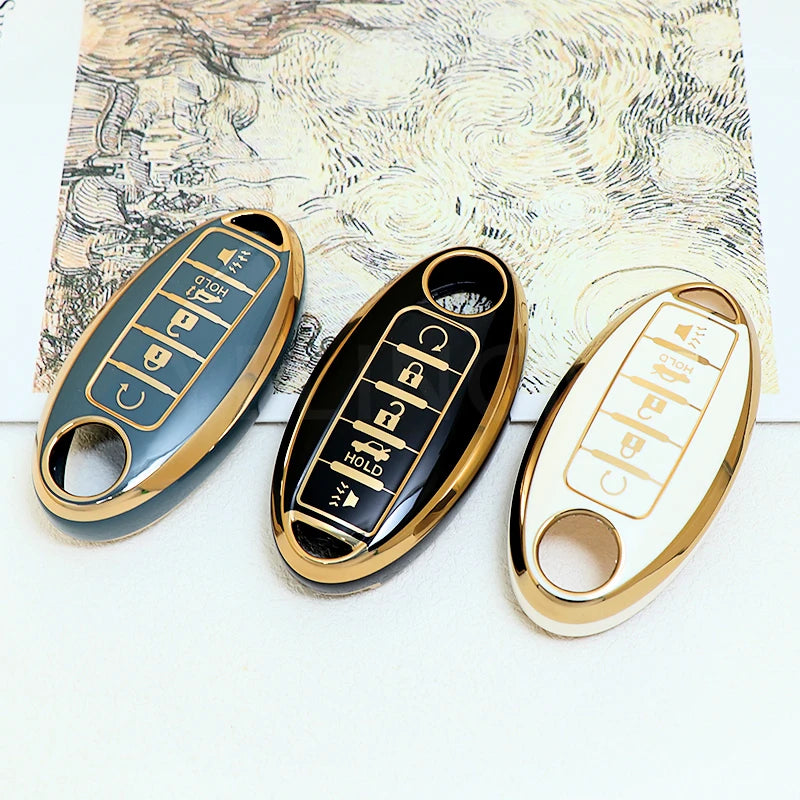 Three gold-colored car key fobs with black and light blue designs resting on a textured paper background.